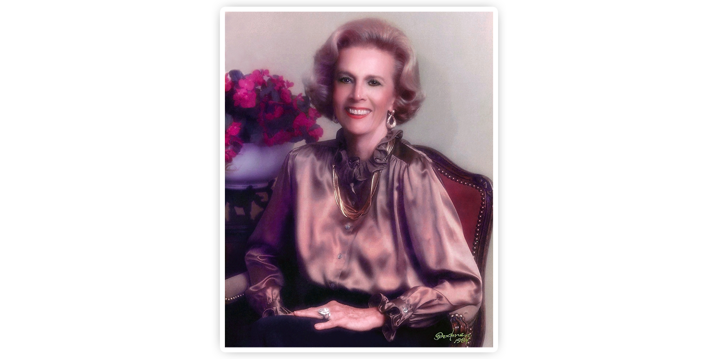 A portrait of Jane Chilton Justin posing for the camera smiling, wearing a brown silk shirt.